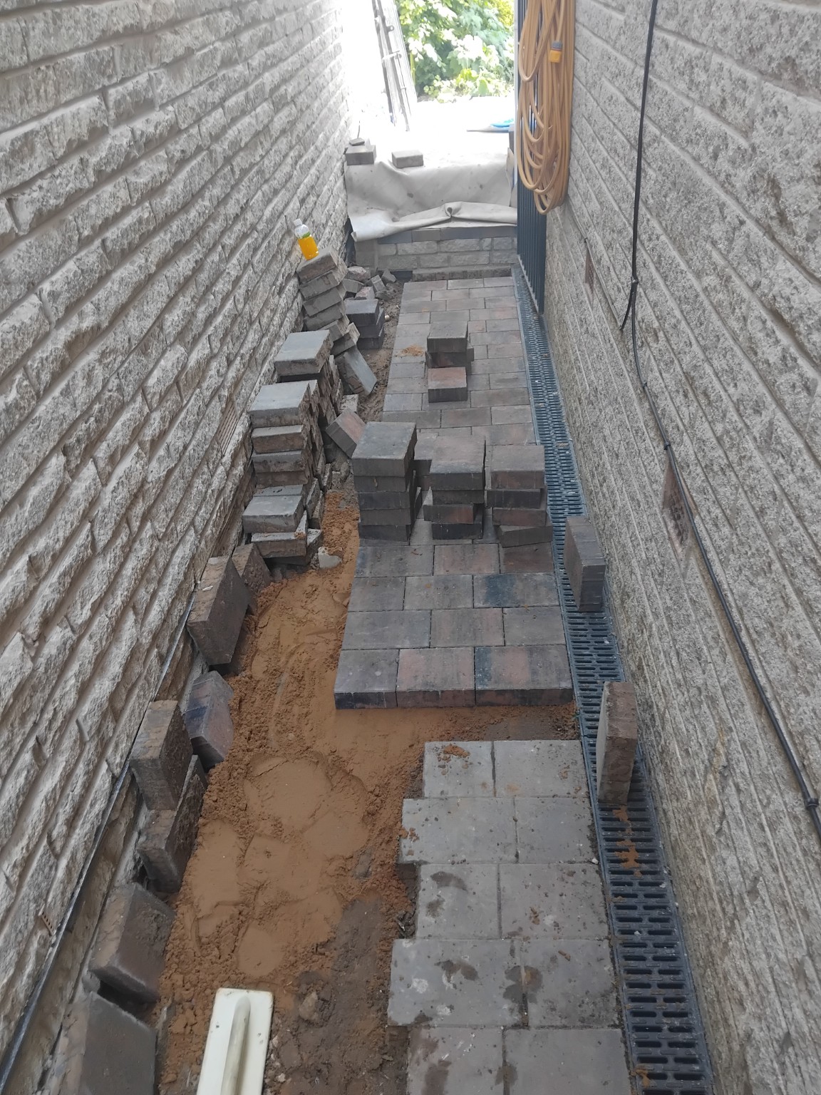 Block paving being laid on a sand bed alongside a linear drainage channel