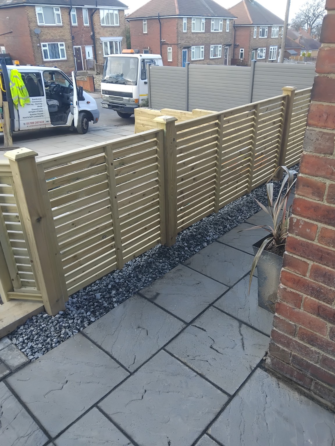 Grey paving beside timber screening and a decorative stone border