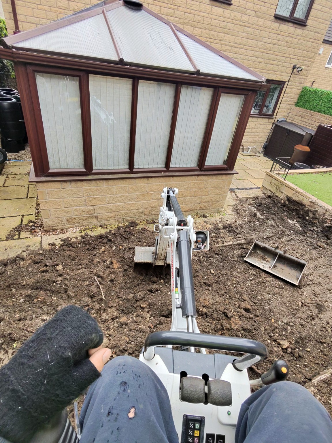 Mini excavator preparing ground in front of an existing conservatory