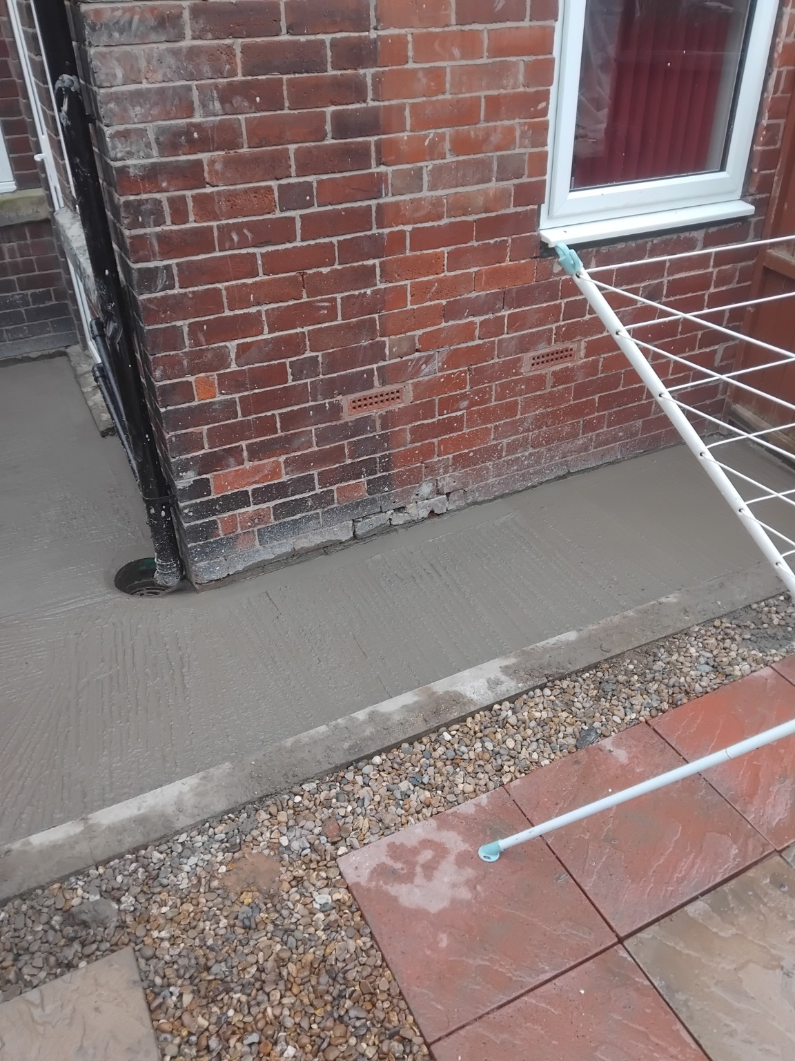 Textured concrete path alongside the brick wall of a house