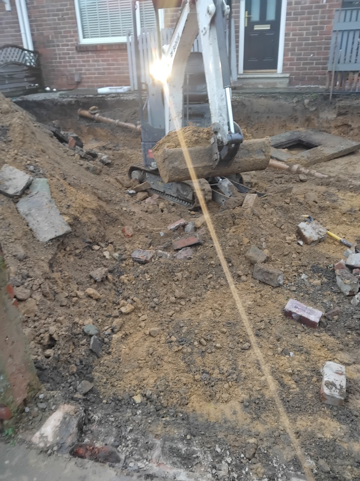 Mini excavator removing old masonry during front garden groundworks