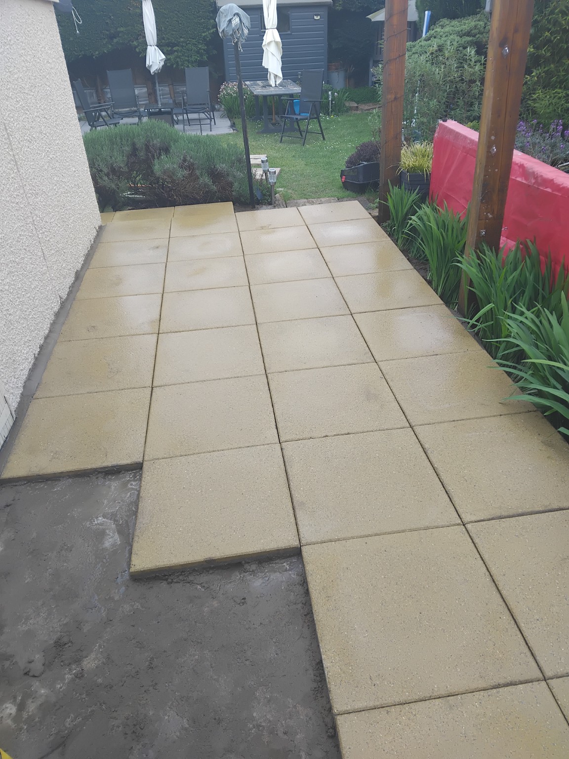 View of newly laid pale patio paving beside a planted garden border