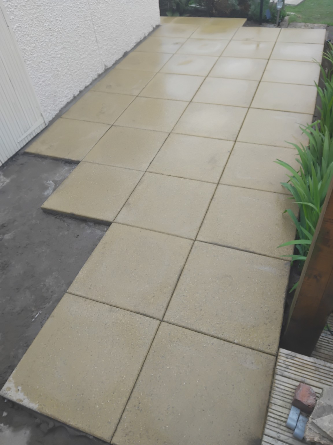Pale paving slabs laid across most of the patio with a small area still in progress