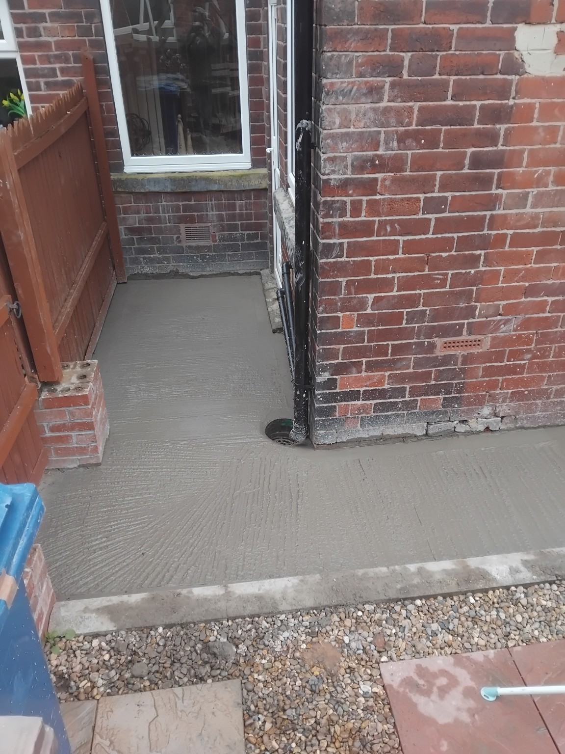 New concrete path wrapping around the corner of a brick house