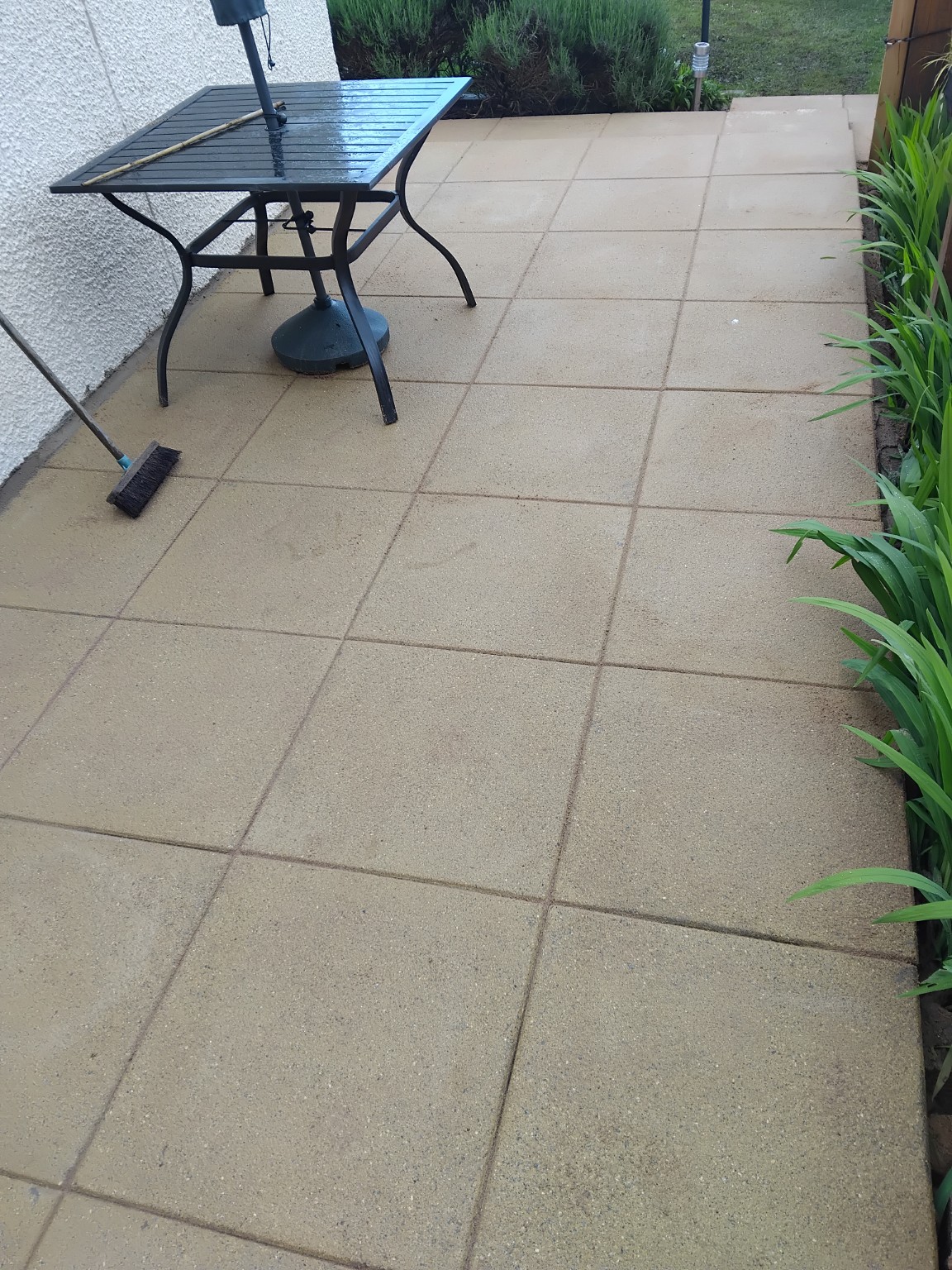 Finished pale paved patio with a garden table and planting alongside