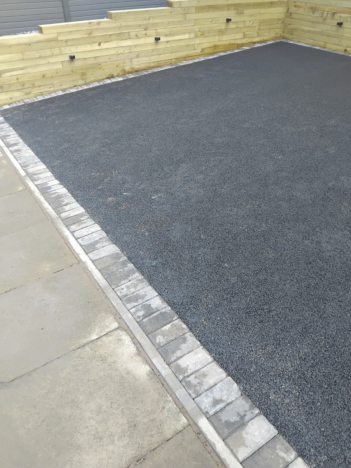 Detail of contrasting block edging beside the finished dark driveway