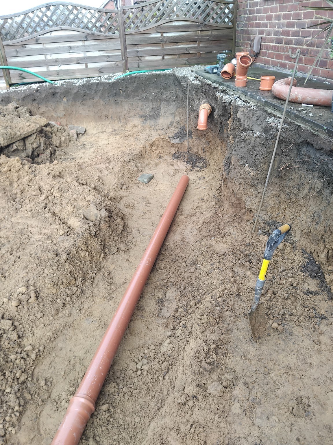 Drainage pipework installed in an excavated trench during driveway groundwork