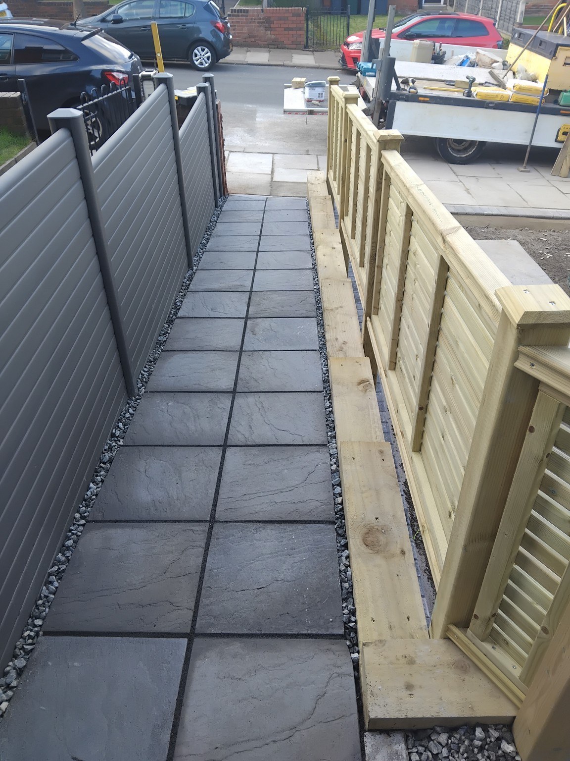 Paved side access path between timber and grey fencing