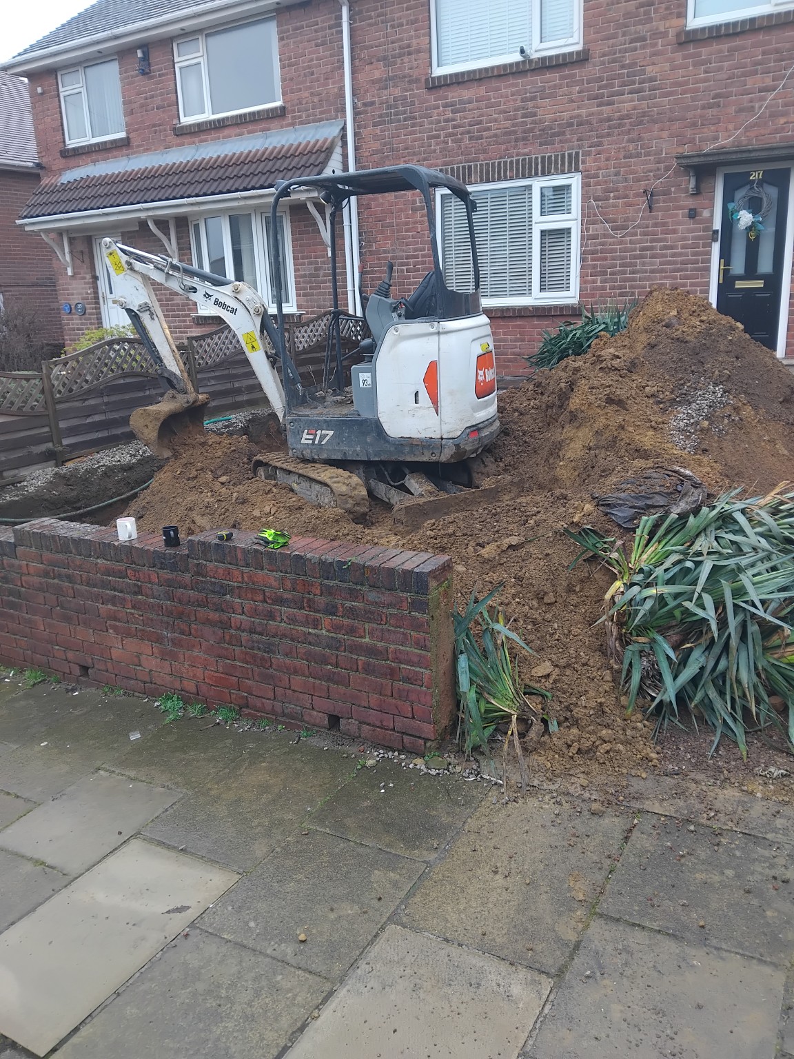 Compact excavator working in a front garden