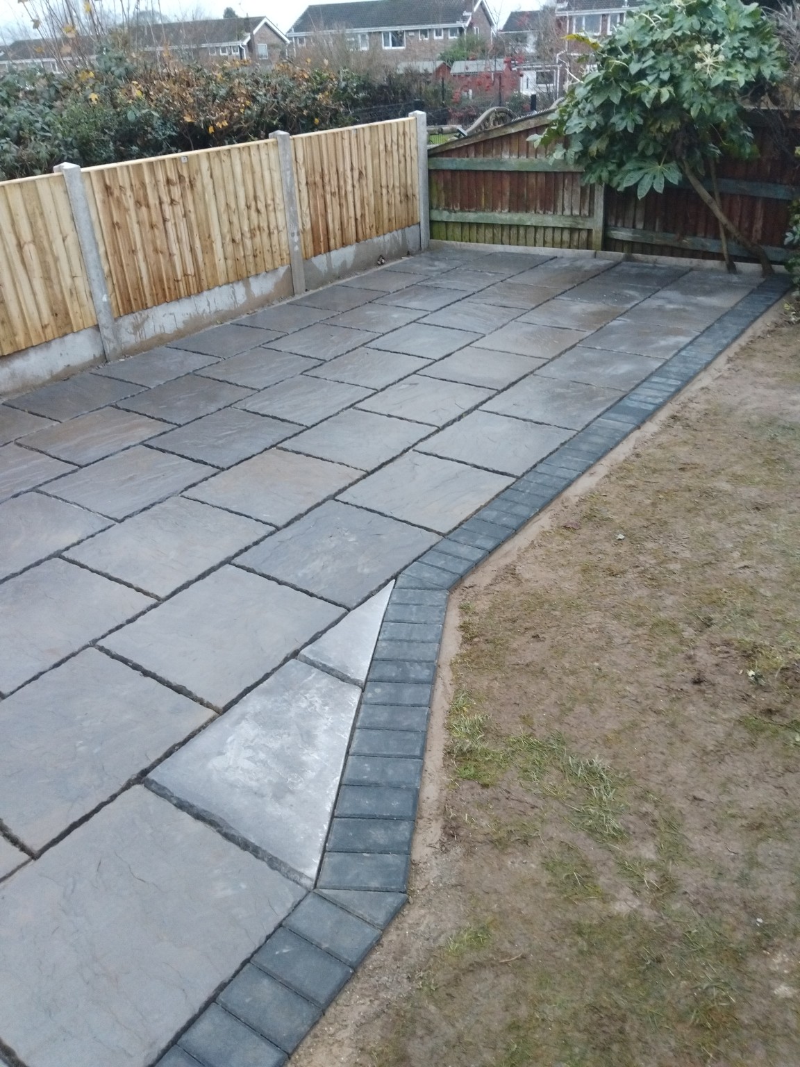 Grey patio paving with a curved dark border